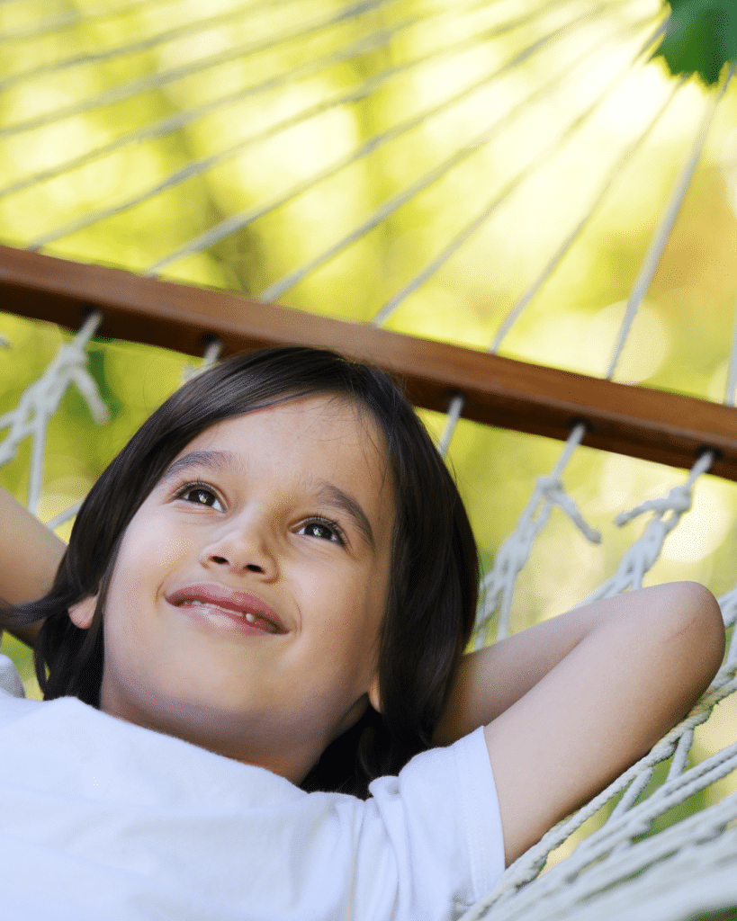 Boy swinging in hammock outside.