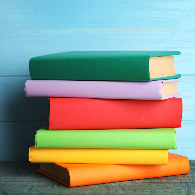 Stack of colorful books on light blue wooden table