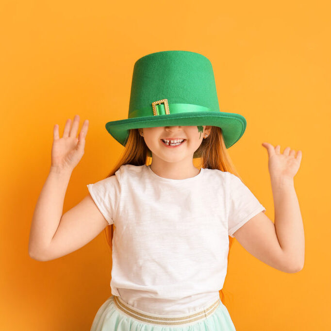 Funny little girl on color background. St. Patrick's Day celebration