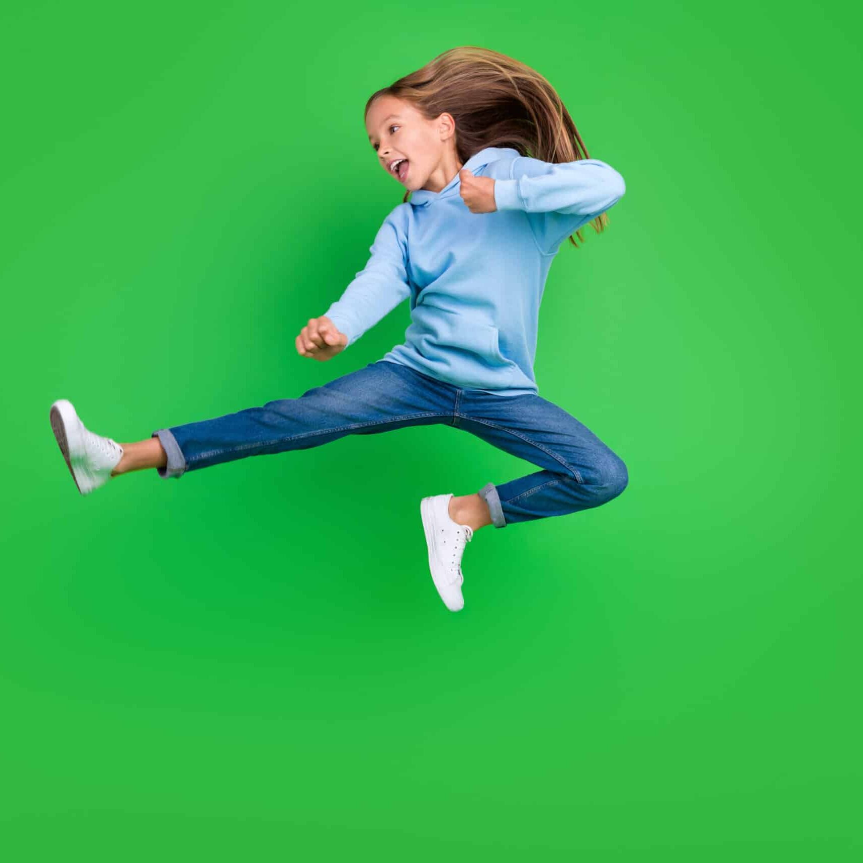 Full body photo of energetic small girl jump practicing martial arts fan dressed trendy blue sportswear isolated on green color background.