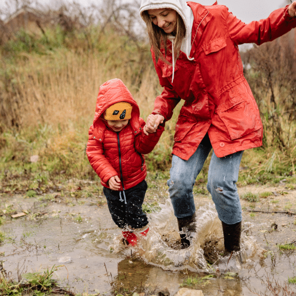 Mother and son jumping in puddle together
